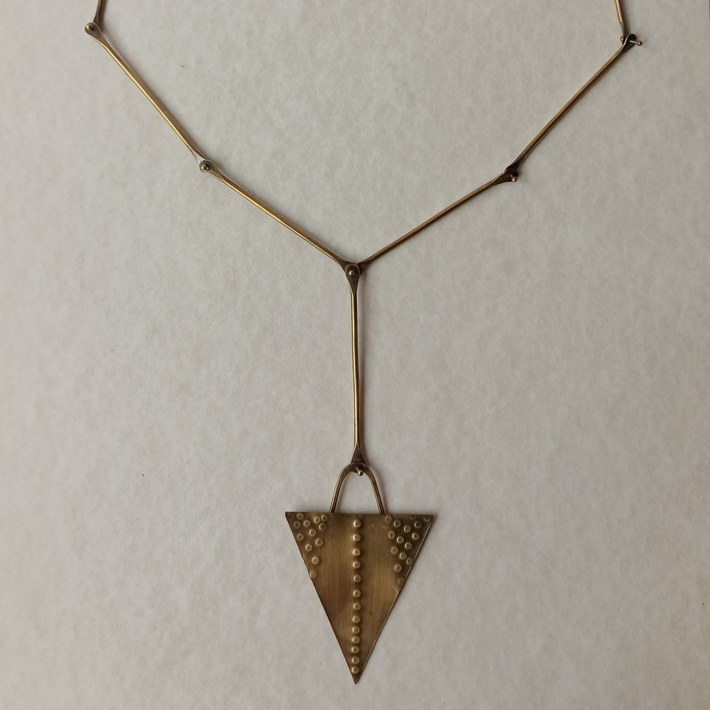 Handmade long necklace from oxidized brass. The center part is made from handtextured brass sheet and the chain is handmade from brass wire. The part that rests on the neck is from black satin cord. A lariat style totally handmade necklace ideal to make your outfit stand out.