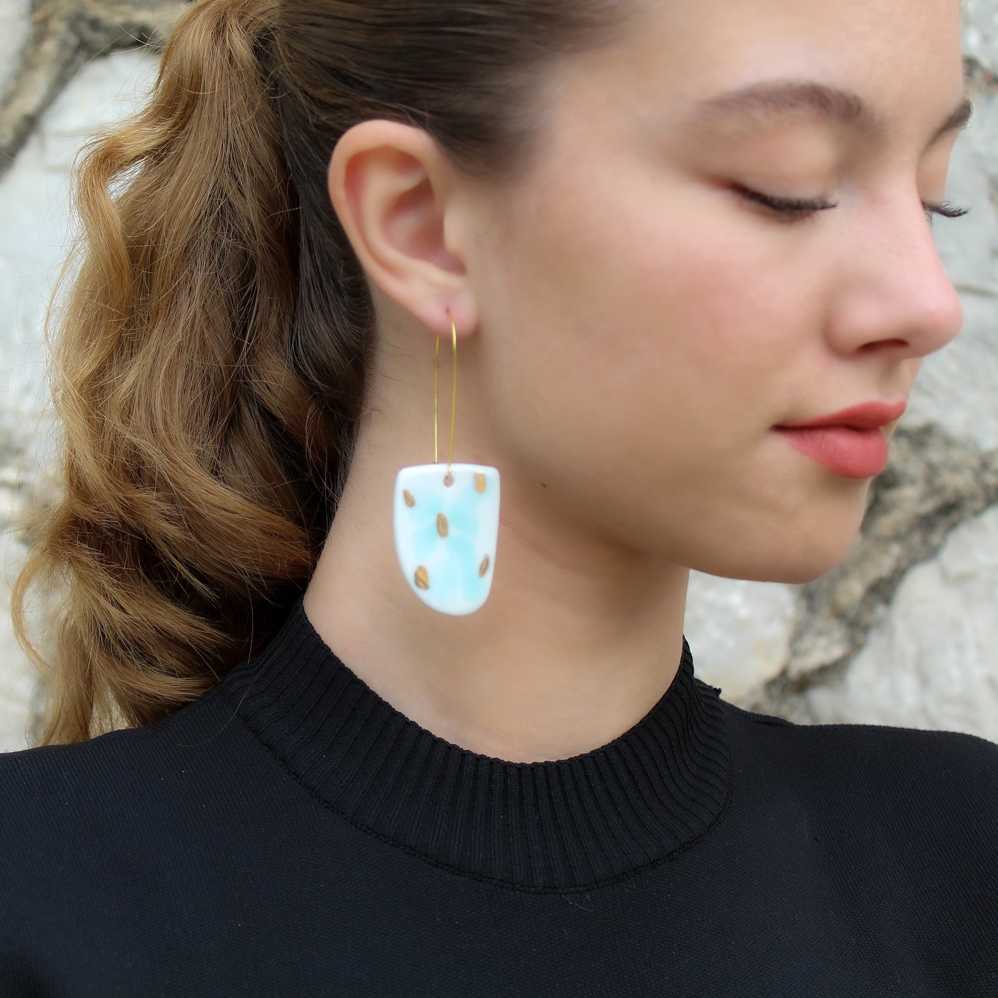 White porcelain drop earrings with aquamarine  and gold luster spots. Hanging from long gold plated  earhooks.